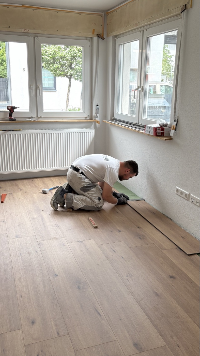 Mitarbeiter verlegt einen neuen Boden in einem hellen Zimmer