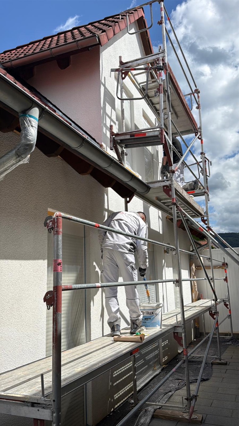 Maler auf dem Gerüst streicht die Fassade eines Wohnhauses