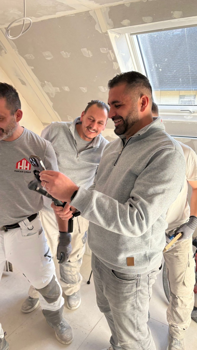 Zwei Teammitglieder begutachten gemeinsam ein Werkzeug im ausgebauten Dachgeschoss