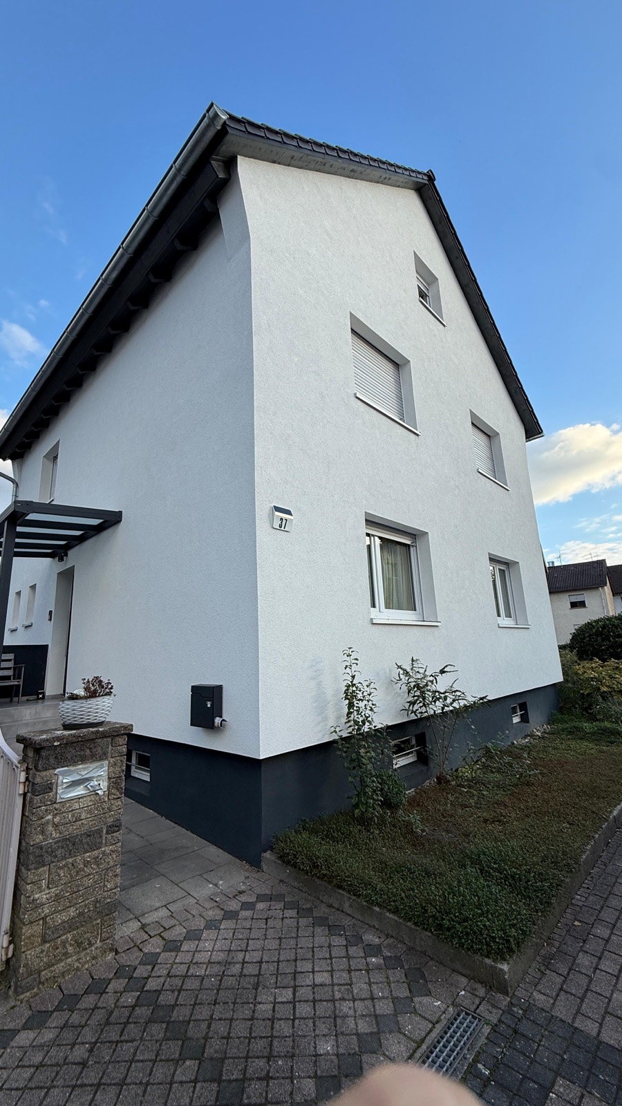 Weiß gestrichene Hausfassade mit dunkel abgesetztem Sockel in Malsch