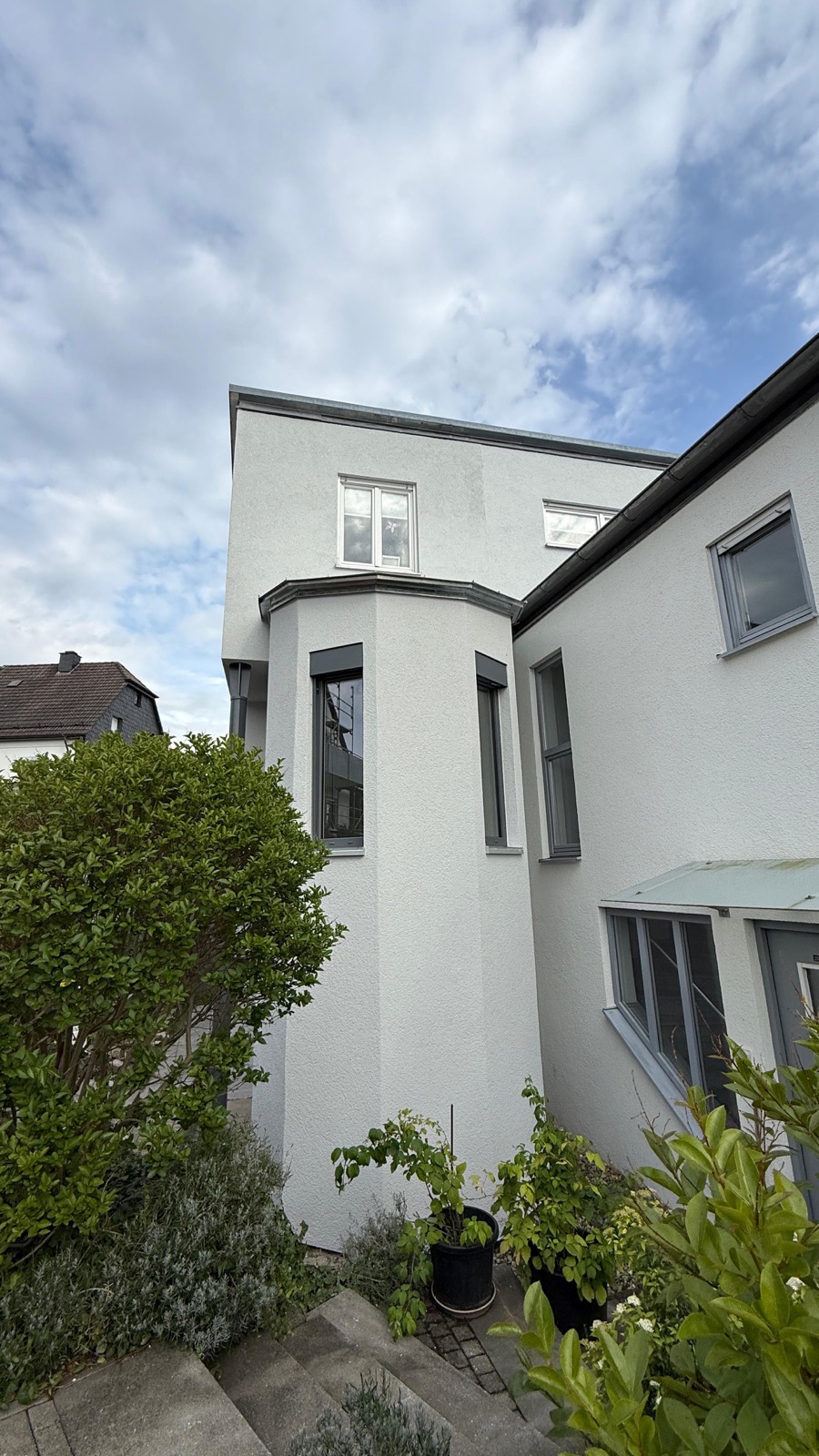 Frisch sanierte weiße Fassade eines Wohnhauses mit Erker in Pfinztal, davor ein gepflegter Garten