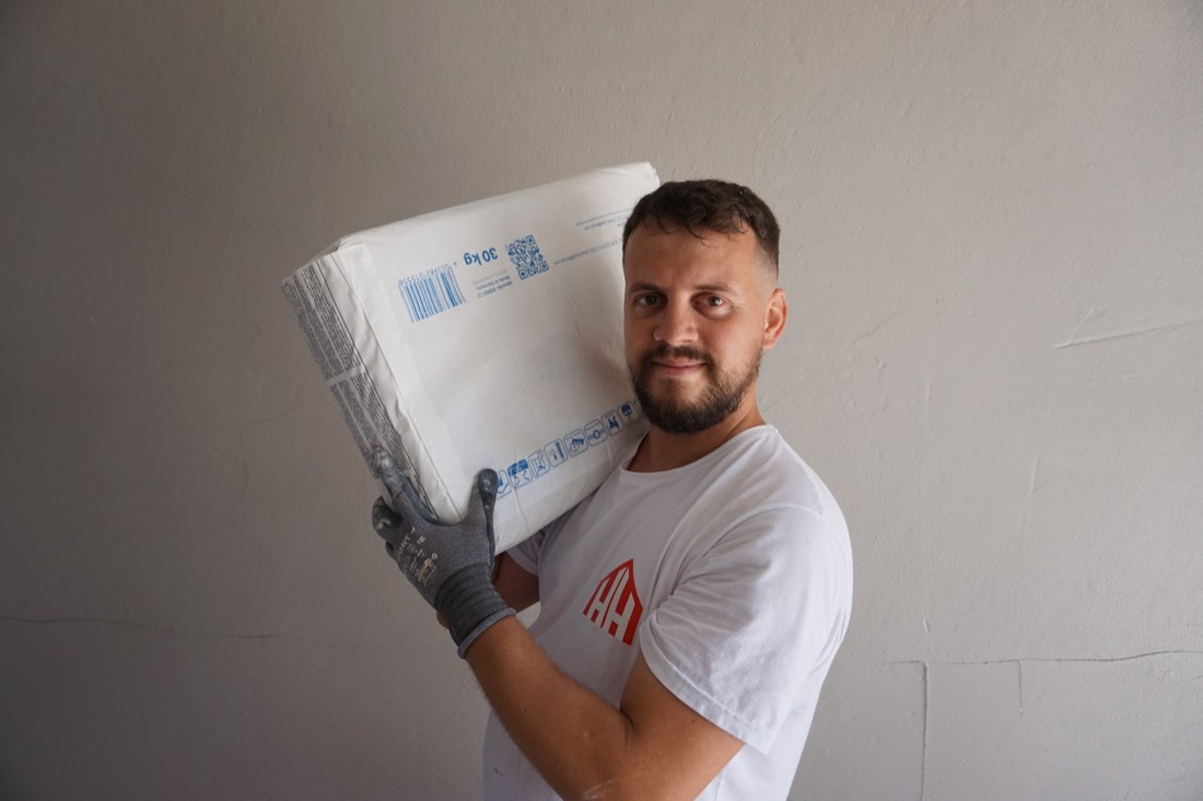 Mitarbeiter der HH Cinar GmbH trägt einen Sack Spachtelmasse über der Schulter